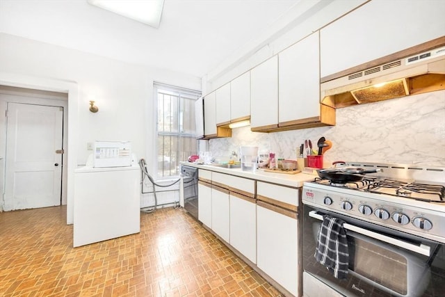 kitchen with stainless steel gas range, under cabinet range hood, tasteful backsplash, and light countertops