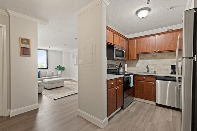 kitchen featuring appliances with stainless steel finishes, light hardwood / wood-style flooring, crown molding, and sink