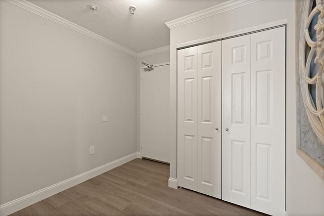 unfurnished bedroom featuring wood-type flooring, crown molding, and a closet