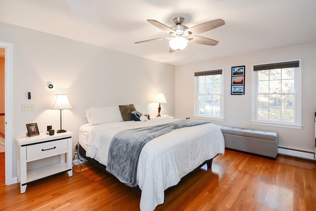 bedroom with ceiling fan, wood-type flooring, and a baseboard radiator