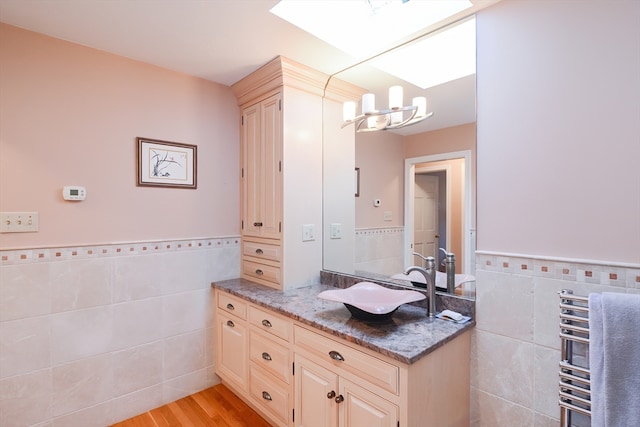 bathroom featuring hardwood / wood-style floors, vanity, tile walls, and radiator