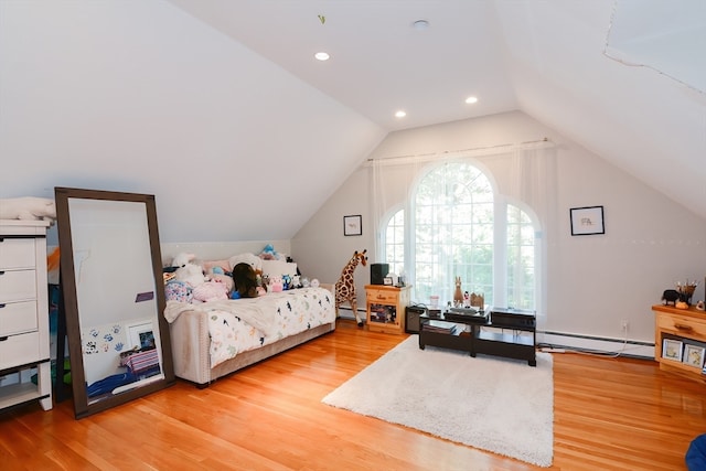 bedroom with light hardwood / wood-style flooring, vaulted ceiling, and a baseboard heating unit