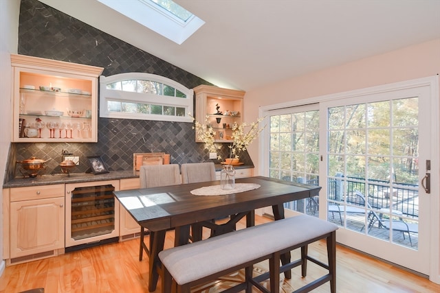 dining area with light wood-type flooring, lofted ceiling with skylight, and a wealth of natural light