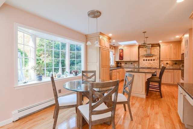 dining area with light wood-type flooring, a skylight, baseboard heating, and sink