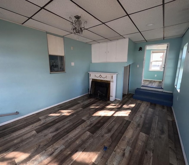 unfurnished living room with a paneled ceiling, dark hardwood / wood-style flooring, and a chandelier