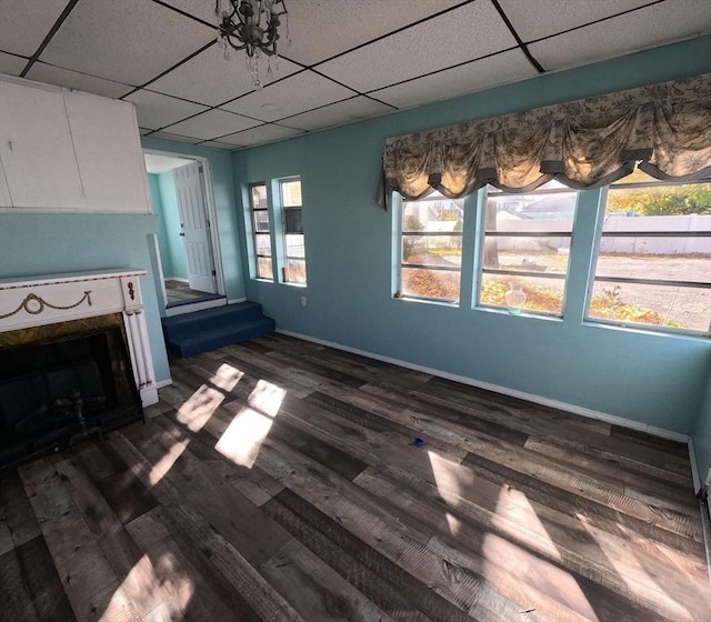 unfurnished living room with a paneled ceiling and dark wood-type flooring