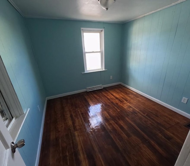 spare room with crown molding, wooden walls, and hardwood / wood-style flooring