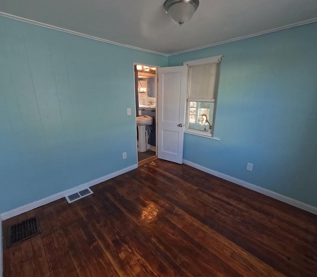 unfurnished bedroom featuring ornamental molding, ensuite bathroom, and dark wood-type flooring