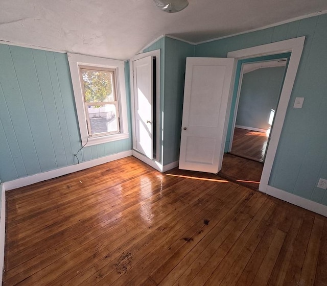 unfurnished bedroom with hardwood / wood-style floors and vaulted ceiling