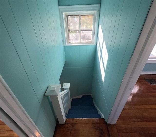 staircase with hardwood / wood-style floors and wooden walls