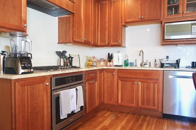 18 Rushmore St, Boston, MA 02135 - kitchen with stainless steel appliances, a sink, backsplash, wall chimney range hood, and light wood finished floors