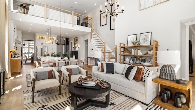 living room with a towering ceiling, light hardwood / wood-style floors, and a chandelier