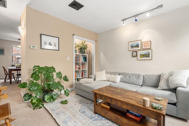 carpeted living area featuring rail lighting and baseboards