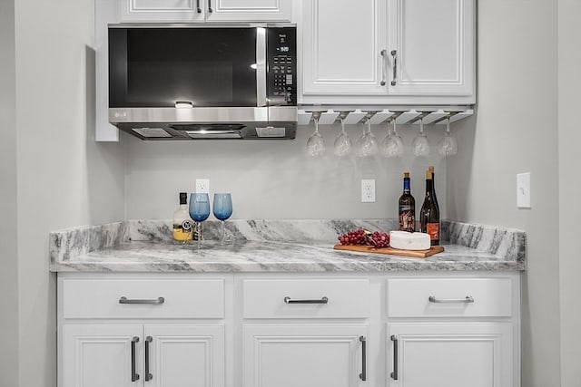 bar with light stone counters and white cabinets