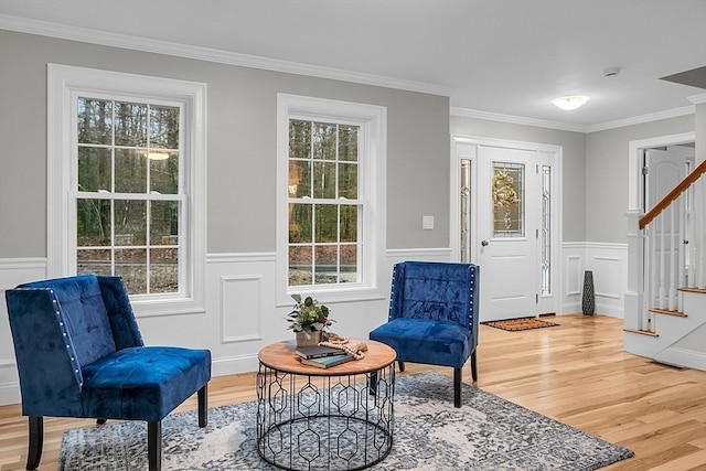 living area featuring a wealth of natural light, ornamental molding, and hardwood / wood-style flooring