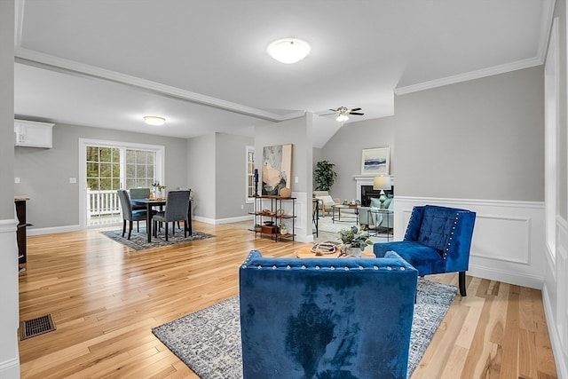 living room with wood-type flooring, ceiling fan, and ornamental molding