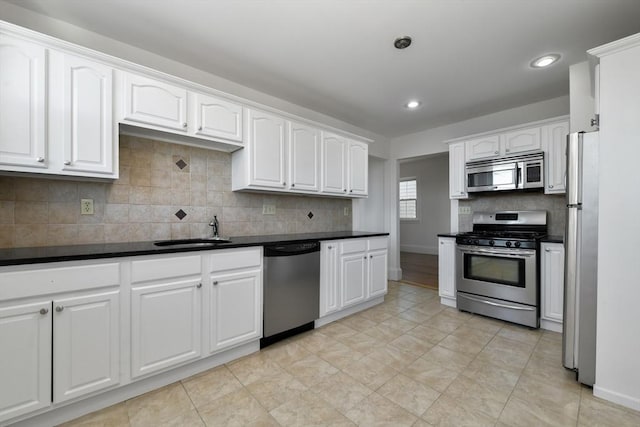 kitchen featuring dark countertops, white cabinetry, appliances with stainless steel finishes, and a sink