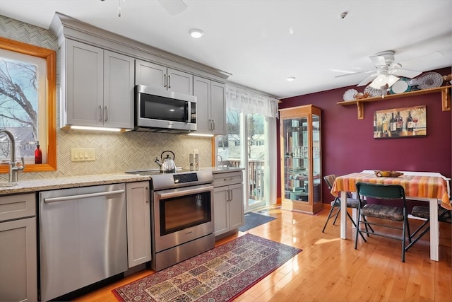 241 Broadway Rd Unit 56, Dracut, MA 01826 - kitchen with stainless steel appliances, a ceiling fan, gray cabinets, light wood-style floors, and backsplash