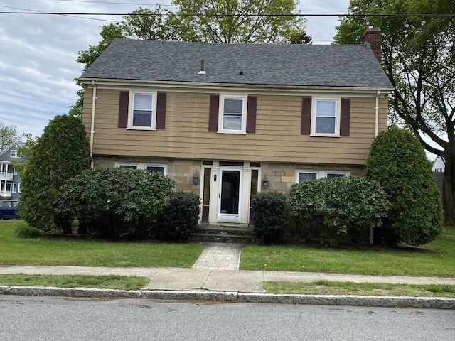 452 W Clinton St, New Bedford, MA 02740 - colonial house featuring a chimney, a shingled roof, a front lawn, and stone siding