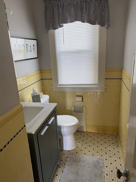 452 W Clinton St, New Bedford, MA 02740 - bathroom with radiator heating unit, tile walls, wainscoting, toilet, and vanity