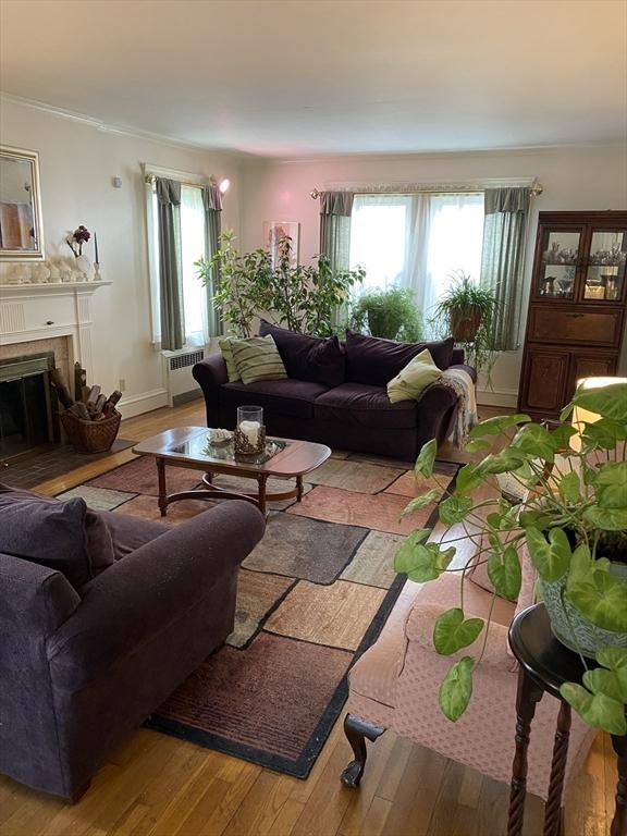 452 W Clinton St, New Bedford, MA 02740 - living area featuring a fireplace, wood-type flooring, crown molding, radiator heating unit, and baseboards