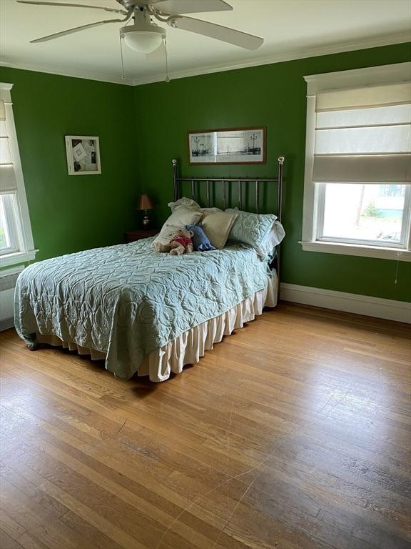 452 W Clinton St, New Bedford, MA 02740 - bedroom featuring multiple windows, crown molding, wood finished floors, ceiling fan, and baseboards