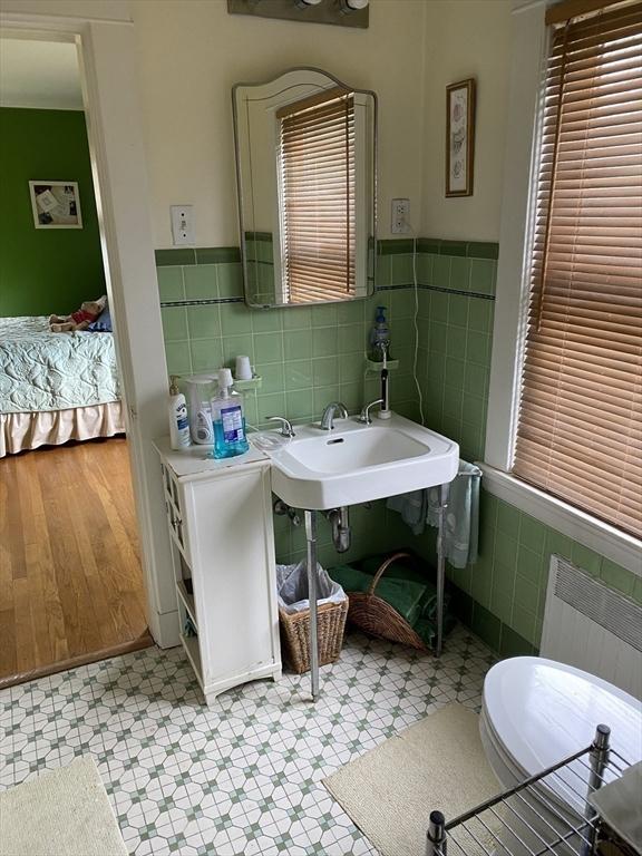 452 W Clinton St, New Bedford, MA 02740 - bathroom featuring tile walls, radiator, tile patterned floors, and wainscoting