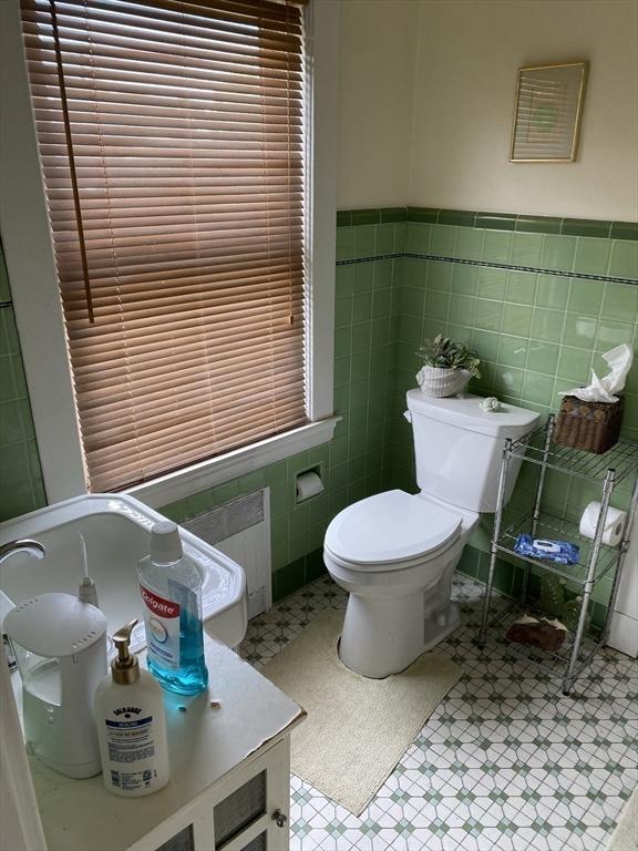 452 W Clinton St, New Bedford, MA 02740 - bathroom featuring tile patterned floors, toilet, radiator, tile walls, and a wainscoted wall