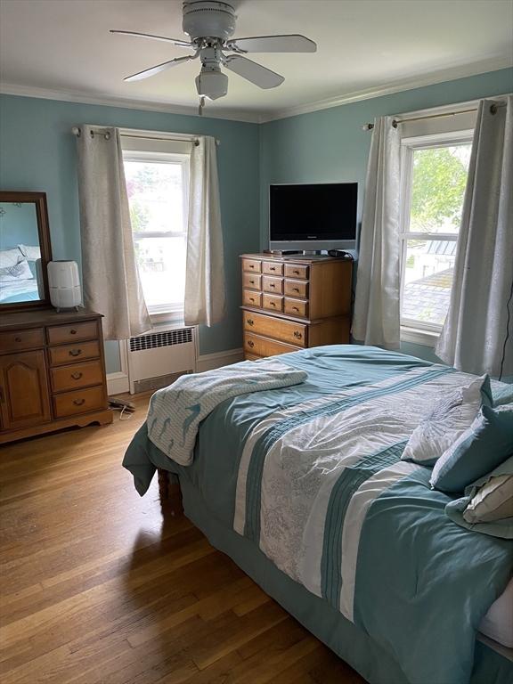 452 W Clinton St, New Bedford, MA 02740 - bedroom with multiple windows, radiator heating unit, ornamental molding, light wood-style flooring, and a ceiling fan