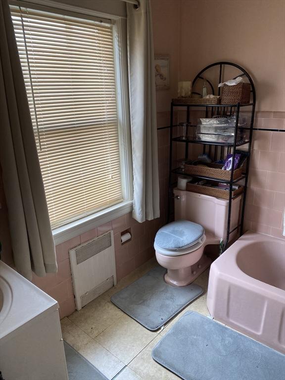452 W Clinton St, New Bedford, MA 02740 - bathroom with radiator heating unit, tile walls, toilet, a bathtub, and tile patterned floors