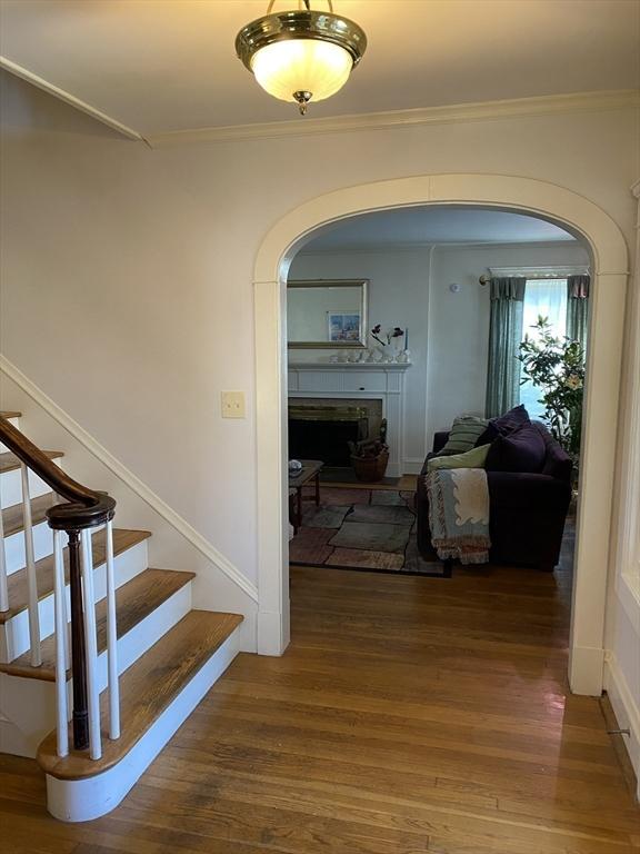 452 W Clinton St, New Bedford, MA 02740 - hallway featuring arched walkways, wood finished floors, crown molding, and stairs