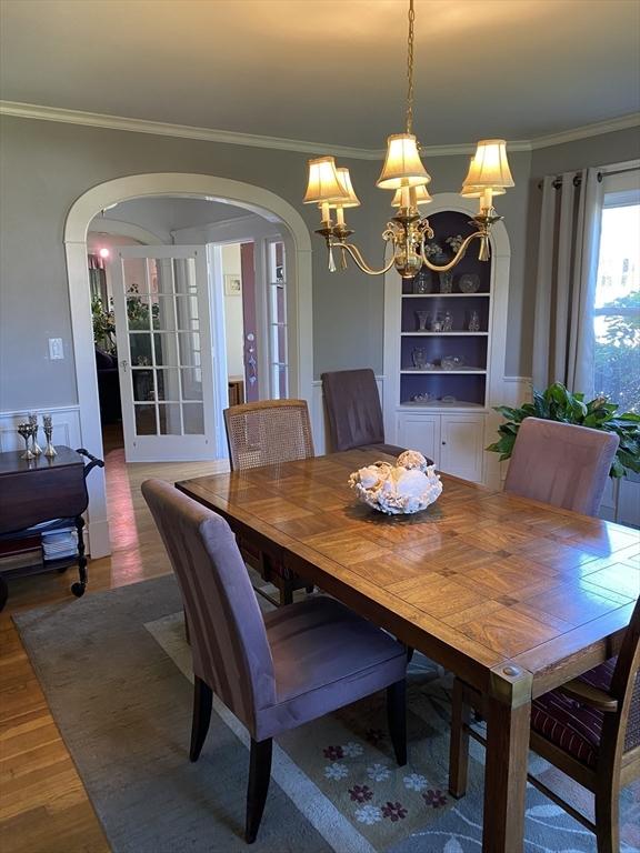 452 W Clinton St, New Bedford, MA 02740 - dining area featuring arched walkways, ornamental molding, a chandelier, wood finished floors, and built in features
