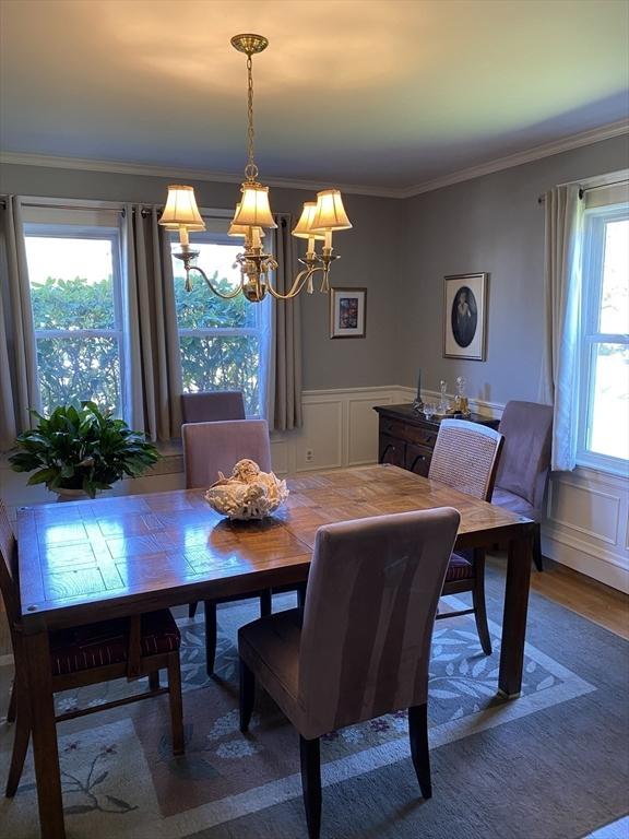 452 W Clinton St, New Bedford, MA 02740 - dining area with a chandelier, a decorative wall, wood finished floors, crown molding, and wainscoting