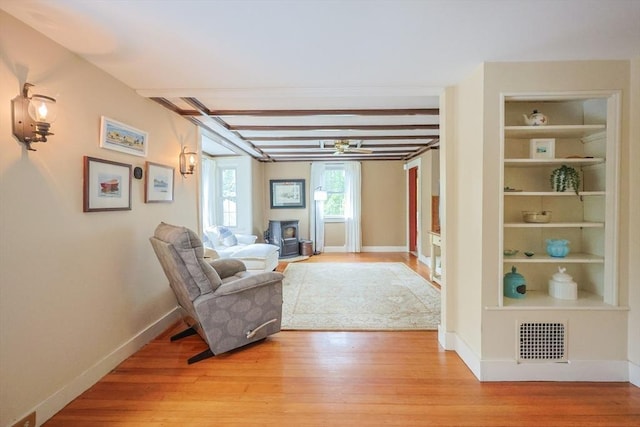 21 Witherell Pl, Plainville, MA 02762 - living area with light wood-style floors, baseboards, built in features, a wood stove, and beam ceiling