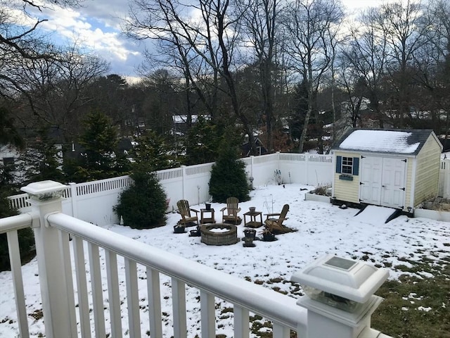 yard layered in snow with a storage unit and an outdoor fire pit