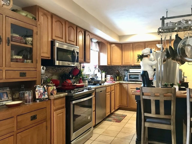 kitchen featuring light tile patterned floors, decorative backsplash, stainless steel appliances, and sink