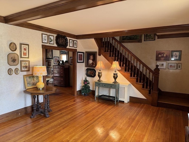 interior space with wood-type flooring, ornamental molding, and beamed ceiling