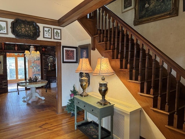 staircase featuring ornamental molding, hardwood / wood-style floors, and a notable chandelier