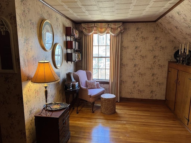 sitting room with crown molding and wood-type flooring