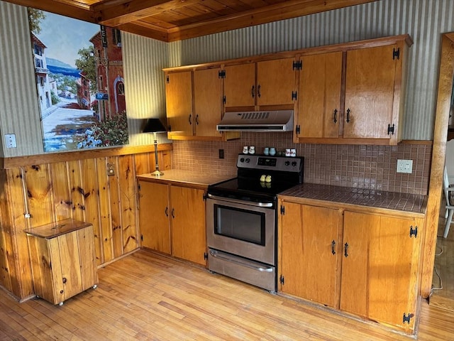 kitchen with tasteful backsplash, light hardwood / wood-style flooring, beam ceiling, and electric stove