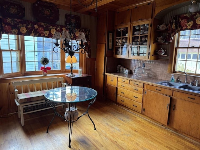 kitchen with tasteful backsplash, sink, light hardwood / wood-style flooring, and hanging light fixtures