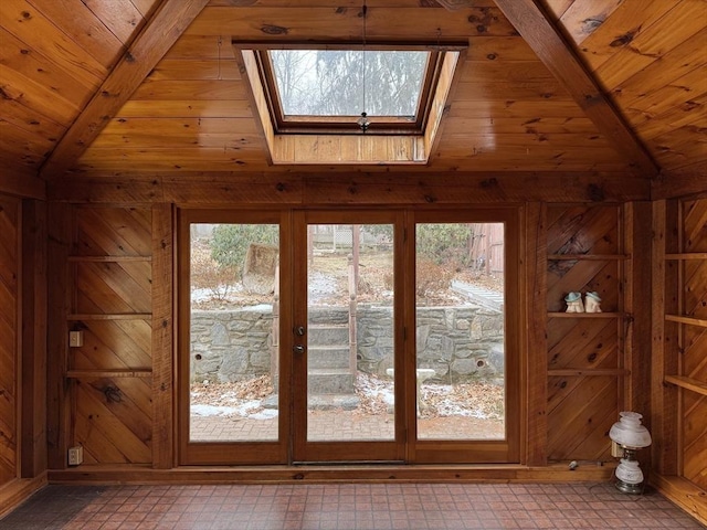 entryway with wood walls, wooden ceiling, a wealth of natural light, and vaulted ceiling with beams