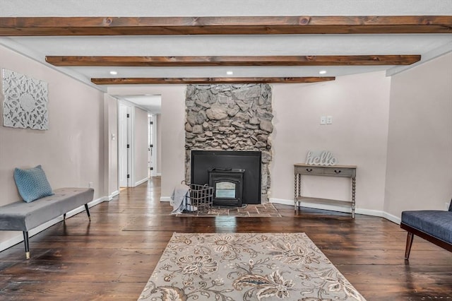 living room featuring dark wood-style flooring, beamed ceiling, a wood stove, and baseboards