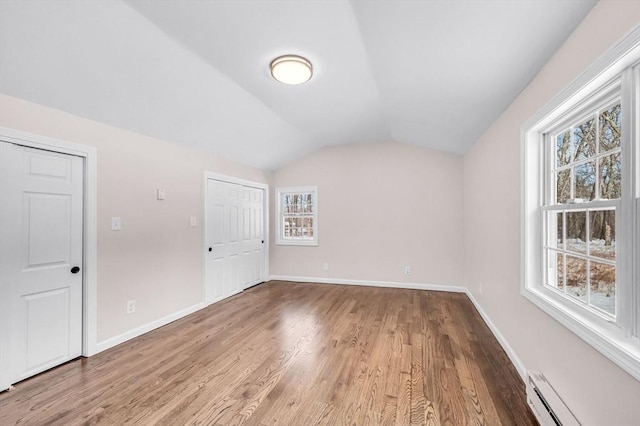 bonus room with vaulted ceiling, baseboard heating, wood finished floors, and baseboards