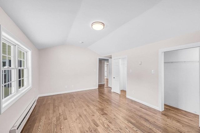 unfurnished bedroom featuring light wood finished floors, a baseboard radiator, baseboards, and vaulted ceiling