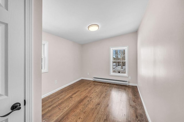 empty room with a baseboard radiator, wood finished floors, and baseboards