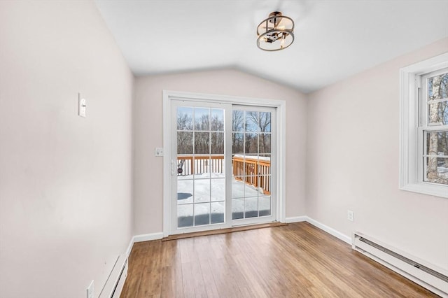 entryway with a baseboard heating unit, light wood-style floors, vaulted ceiling, and baseboards