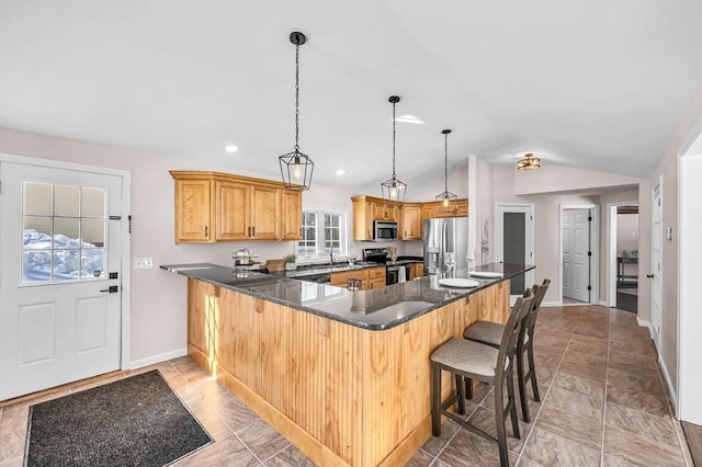 kitchen featuring lofted ceiling, hanging light fixtures, a peninsula, stainless steel appliances, and a kitchen bar