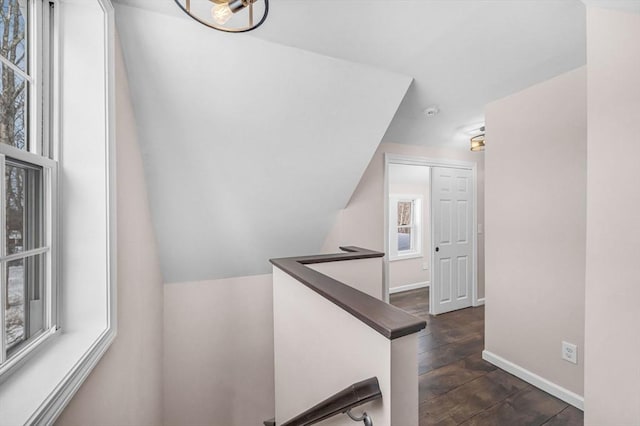 staircase featuring baseboards, vaulted ceiling, and wood finished floors