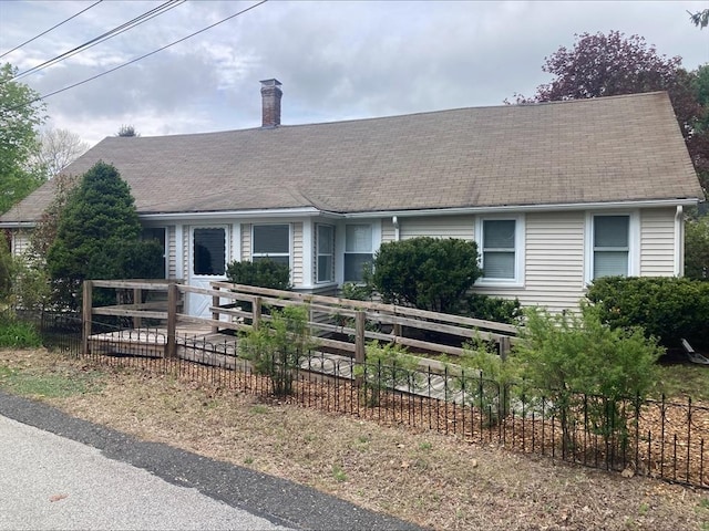 view of front of property with a shingled roof, a chimney, and fence private yard